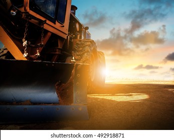 Silhouette Wheel loader Excavator with backhoe unloading sand at eathmoving works in construction site over blurred natural background sunset pastel. heavy industry and safety at work concept.
