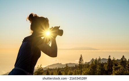 Silhouette of woman with camera. Woman takes photo of La Gomera Island in the rays of the setting sun. Tenerife Island.