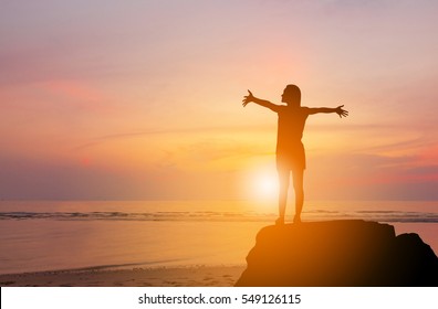 Silhouette of Woman Celebration Success Happiness on a Stone Evening Sky Sunset at Beach Background, Sport and active life Concept.