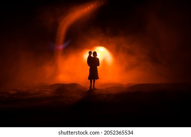 Silhouette of woman with child walking at cemetery at night. Horror Halloween concept. Artwork table decoration with light and smoke. Selective focus