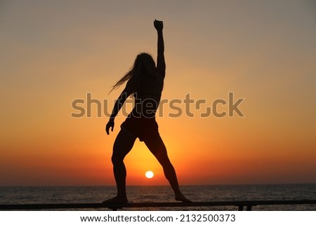 Silhouette of a woman dancing against a sea background