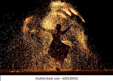 Silhouette of a woman dancing amongst a shower of fire sparks