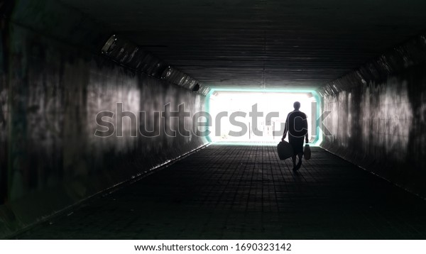 Silhouette of woman in dark underpass. Danger of\
loneliness and insecurity in\
city