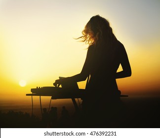 Silhouette of a woman dj at sunset