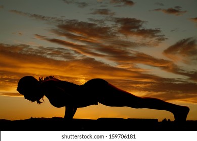 A silhouette of a woman doing a push up.