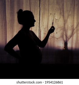 Silhouette of a woman during pregnancy with a syringe in her hand. Pregnant woman gets an injection, a concept of drug problems - Shutterstock ID 1954126861