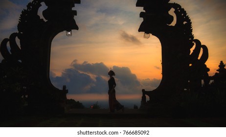 Silhouette Of Woman Full Length At The Balinese Traditional Gates At The Top Of Pura Besakih At Sunset.