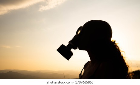 Silhouette Of A Woman With A Gas Mask During A Sunset. Concept: Ecology, There Is No Planet B	