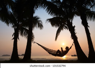 silhouette of woman in hammock at sunset on the beach