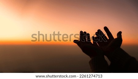 Silhouette of woman hands praying for worship God at sky background. Christians pray to jesus christ for calmness. In morning people got to a quiet place and prayed. Banner with copy space.