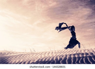 Silhouette of a woman holding a blowing scarf in the dunes. - Powered by Shutterstock