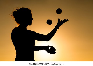 Silhouette of a Woman Juggling with Balls at Sunset