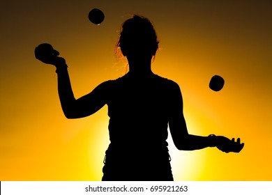 Silhouette of a Woman Juggling with Balls at Sunset