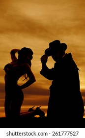 A Silhouette Of A Woman Kneeling With Her Cowboy Behind Her.