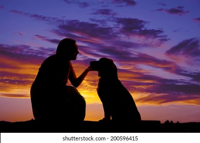 A Silhouette Of A Woman Kneeling And Talking To Her Pet Dog.