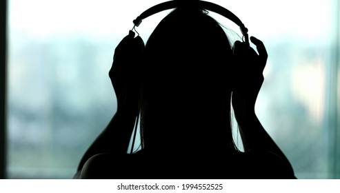 Silhouette Of Woman Listening To Audio, Back Of Person Removing Headphones