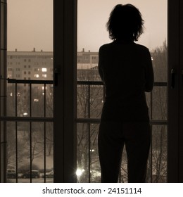 Silhouette Of Woman Looking Out Of Window