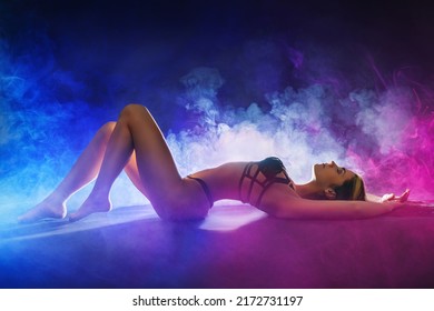  silhouette of a woman lying on the floor in her underwear photo. Hot woman on neon fire and smoke - concept.