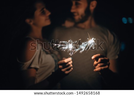 Silhouette woman and man holding a burning sparkler firework bengal light