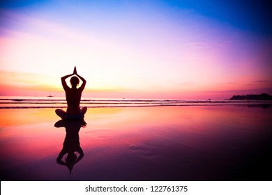 Silhouette of a woman meditating on the beach at sunset - Powered by Shutterstock