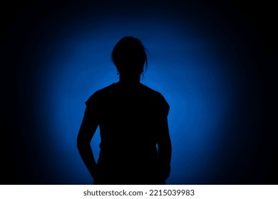 Silhouette Of A Woman On A Round Blue Spot On A Black Background