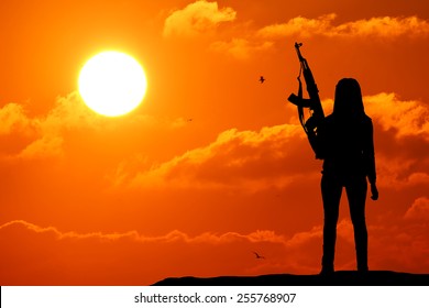 A Silhouette Of A Woman Pointing Her Gun In The Sky.