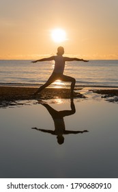 Silhouette Of Woman Practicing The Warrior 1 Yoga On The Beach At Morning Sunset Scene. (Virabhadrasana II Pose)	