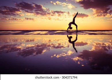silhouette of woman practicing yoga on the beach at sunset