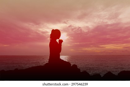 Silhouette of woman praying over beautiful sunset background