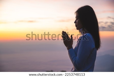 Silhouette of woman  praying over beautiful sunrise background, beautiful landscape, pay homage, spirituality and religion,man praying to god. Christianity concept.