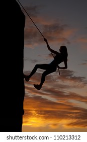 A Silhouette Of A Woman Rock Climbing With A Beautiful Sky Behind Her.