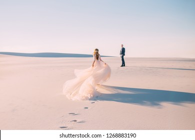silhouette woman runs meet man. Dress  very long train fabric flies wind. tourist Art Photo back without face turned away rear view. UAE Dubai Desert white sand sunset concept happy Valentine's Day