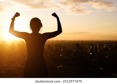 Silhouette of woman showing strong muscle strength arms flexed posing, feels about her success achievement in a big city at morning. Women empowerment, equality, healthy strength and courage concept. - Powered by Shutterstock