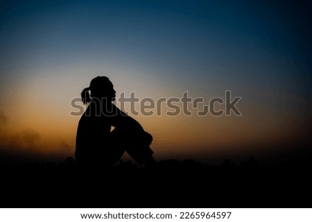 Silhouette of a woman sitdown with so sad in the sunset.