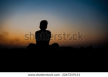 Silhouette of a woman sitdown with so sad in the sunset.