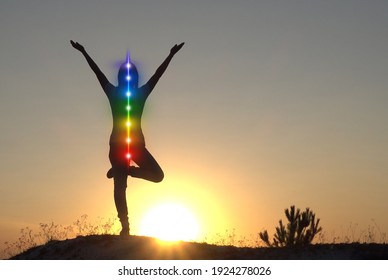 Silhouette of woman sits in a Upward Salute pose on beach sunset view, glowing seven all chakra. Kundalini energy. girl practicing yoga meditation outdoors