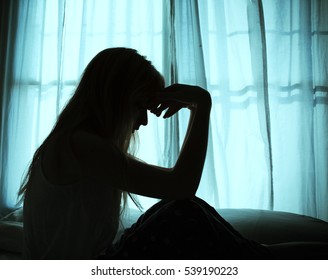 Silhouette Of Woman Sitting In Bed By Window