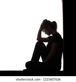 Silhouette Of A Woman Sitting On The Floor In A Corner On A White Isolated Background, A Sad Girl Thinking About Problems, Concept Of Depression And Difficult Age