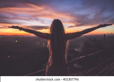 Silhouette Of The Woman Spreading Arms And Standing High On The Viewpoint With Breathtaking View Over Fields In Sunset Light.Chocolate Hills, Bohol Island, Philippines.