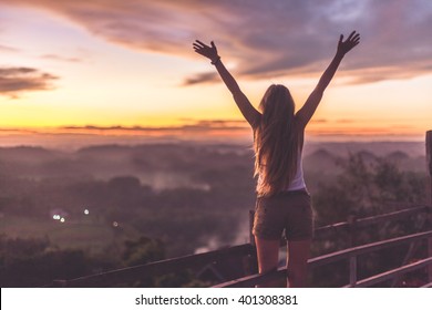 Silhouette Of The Woman Spreading Arms And Standing High On The Viewpoint With Breathtaking View Over Fields In Sunset Light.Chocolate Hills, Bohol Island, Philippines.