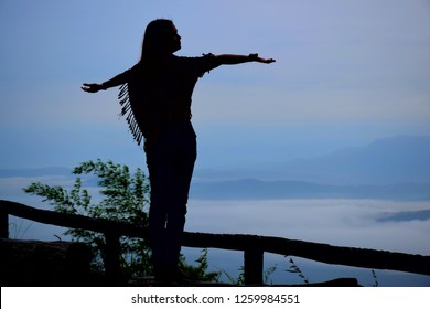  Silhouette of A woman standing arms witch the mist in the morning at Doi Samoe Dao and Pha Hua Sing, Sri Nan National Park, Nan, Thailand - Powered by Shutterstock