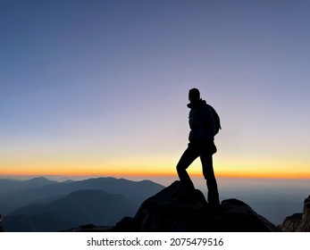 Silhouette of woman standing on top of Djebel Toubkal, the highest mountain of North Africa, at sunrise. Morocco.