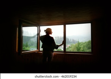 Silhouette Of Woman In Sunshine At Big Wooden Window With View On Sunset In Mountains, Tranquil Moment Or Relax Concept, Space For Text