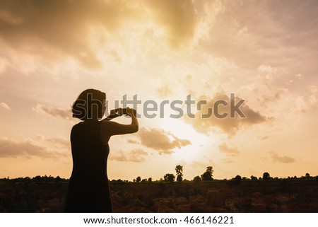 Silhouette woman taking photo with smart phone of landscape,High key.