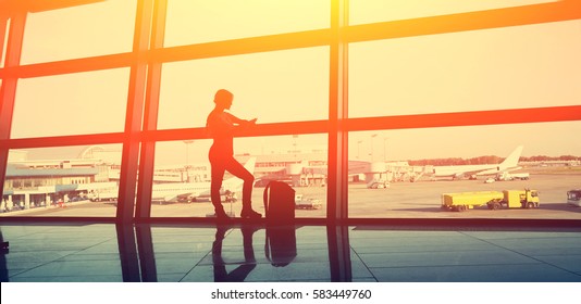 Silhouette Of A Woman Traveler With Backpack In An Airport Lounge. Business And Travel