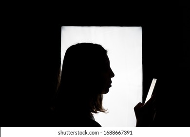 Silhouette Of A Woman Using Smart Phone Mobile. White Big Screen At The Background. Digital Loneliness, Self-isolation, Nomophobia, Digital Poisoning, Quarantine Alone And Hyper Connection Concept.