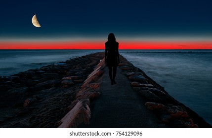 Silhouette Of A Woman Walking By The Sea At Night