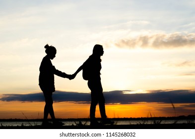 Silhouette of woman walking holding hand during a beautiful sunset. - Shutterstock ID 1145268032