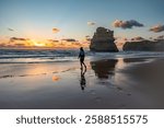 Silhouette of a woman walking on the beach at sunset, at Gibson Steps beach, Great Ocean Road, Princetown, Victoria, Australia