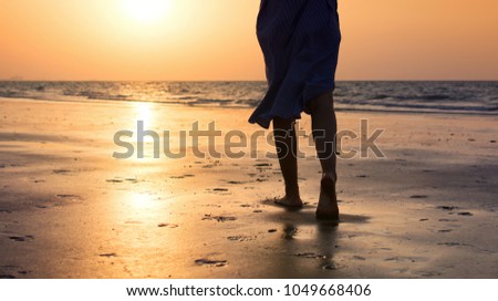 Silhouette of a woman walking on the beach at sunset